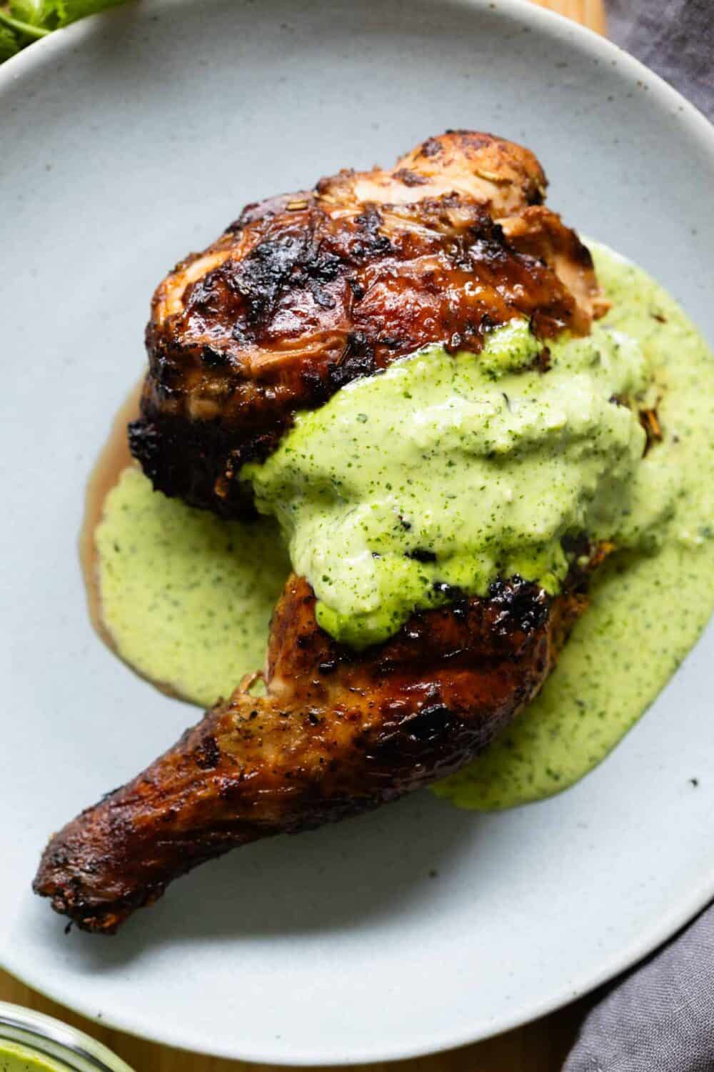 Grilled chicken leg with ají verde sauce on top.