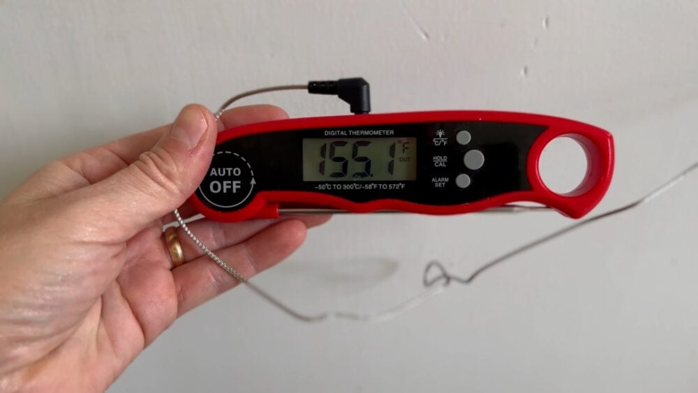 Hand holding meat thermometer reading 155.1°F.